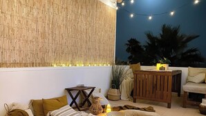 An outdoor seating area with a bamboo wall, string lights, and a wooden table. - Beach villa with ocean view and rooftop cinema (Guia)