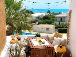 Ein Balkon mit Meerblick, einem Pool und weißen Gebäuden im Hintergrund.