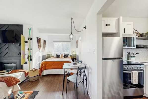 A compact kitchen with a refrigerator, stove, and white cabinets.