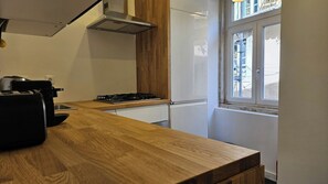 A kitchen with a wooden countertop, a gas stove, a white refrigerator, and a window with a view of the outside. - Historic Center 2-Bedroom Boutique Apartment (Lisbon)