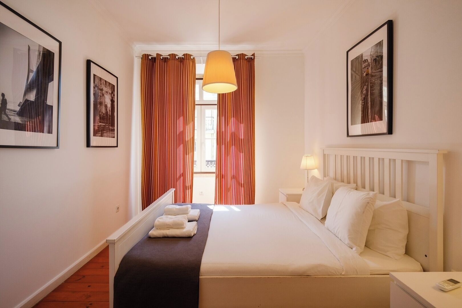 Ein Hotelzimmer mit Bett, Nachttisch, Lampe und Vorhängen.
