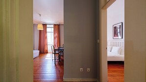 Una stanza con pavimento in legno, un'area pranzo con sedie e tavolo, e un divano bianco.