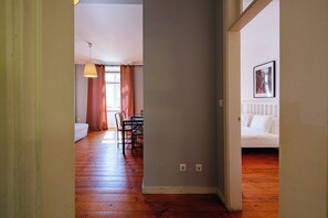 Ein Zimmer mit Holzboden, einem Essbereich mit Stühlen und einem Tisch sowie einem weißen Sofa.