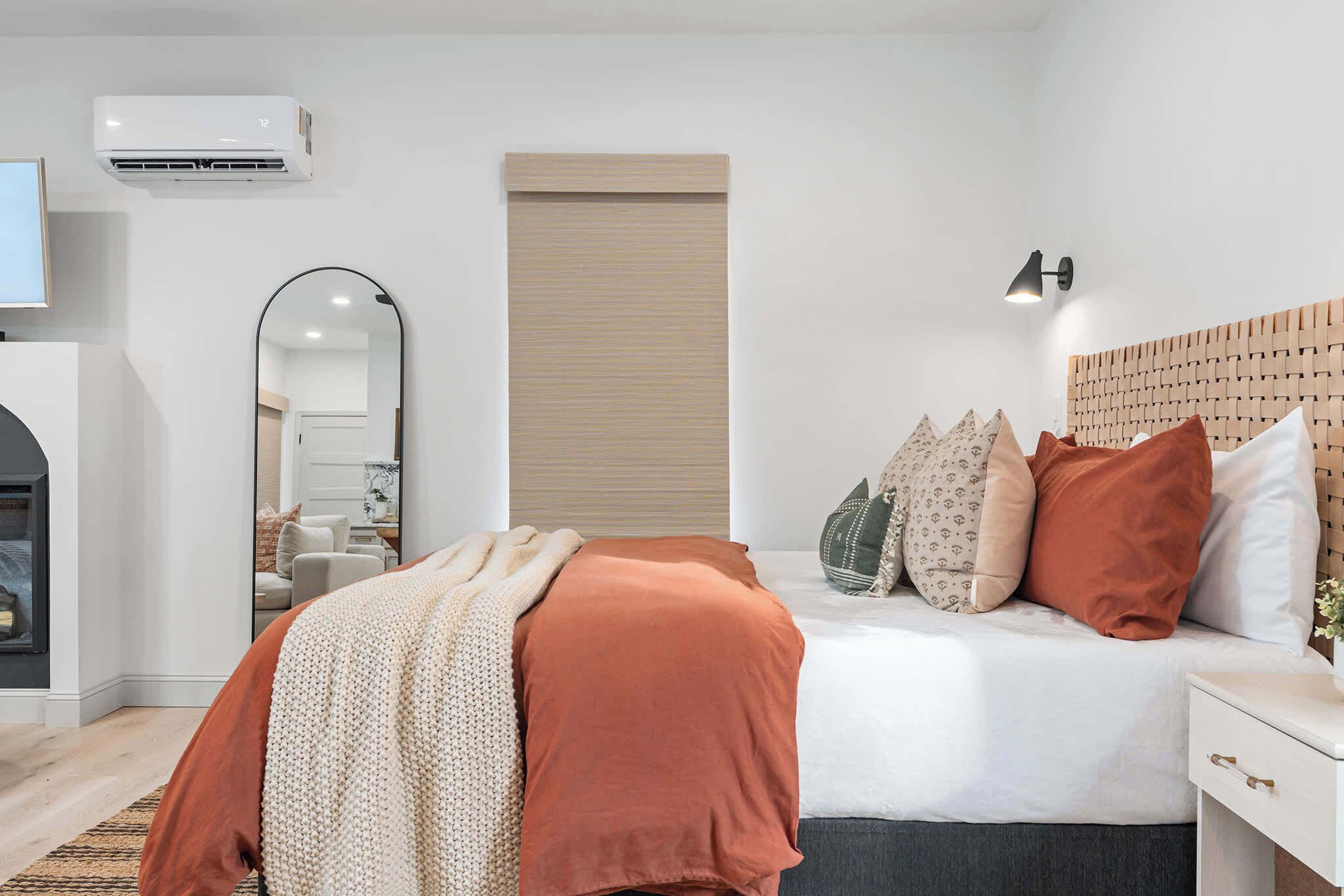 Un dormitorio moderno con cama, mesita de noche y aire acondicionado instalado en la pared.