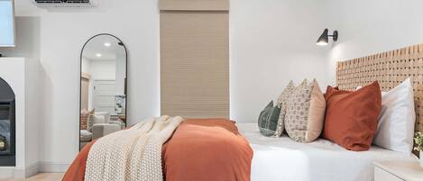 Un dormitorio moderno con cama, mesita de noche y aire acondicionado instalado en la pared.