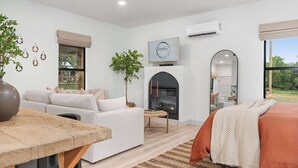 Un dormitorio moderno con sofá, cama, chimenea y un ventanal grande.