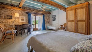 Ein Schlafzimmer mit einem großen Bett, einem Holzschrank, einer Steinwand und einem Deckenventilator.