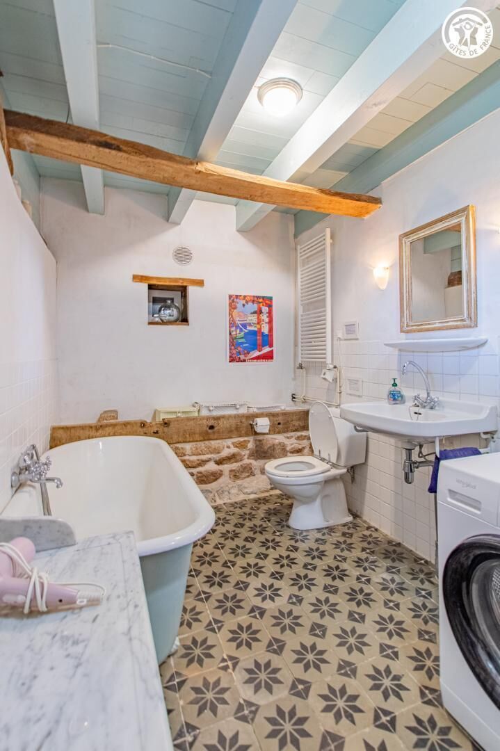 Baño con bañera, inodoro, lavamanos y lavadora.