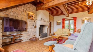 Una sala de estar acogedora con chimenea de piedra, televisor y asientos cómodos.