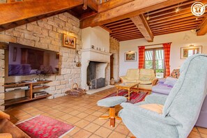 A cozy living room with a stone fireplace, a television, and comfortable seating. - Gîte de la Chaume - GOURDON (GOURDON)