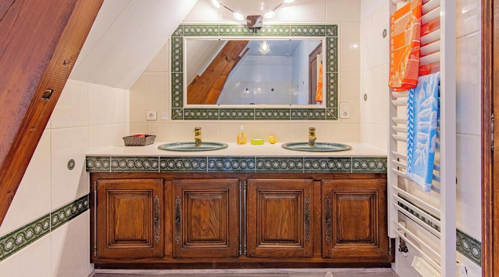 A bathroom with a wooden vanity, two sinks, a mirror, and a towel rack.