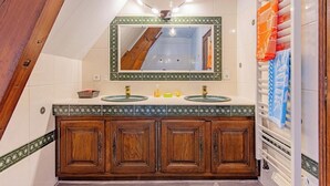 Un baño con tocador de madera, dos lavamanos, un espejo y un perchero para toallas.