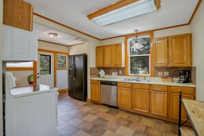 A compact kitchen with wooden cabinets, a built-in dishwasher, and a refrigerator. - 2 Bedroom Cabin near Trout Pond with Private Hot Tub (Estes Park)