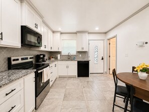 A modern kitchen with white cabinets, a black stove, and a granite countertop.