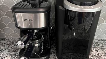 Two coffee makers on a granite countertop with a tiled backsplash.