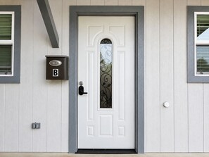 A white door with a decorative glass panel, a mail slot, and a doorbell.