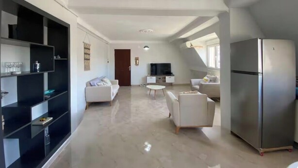 A spacious living area with a sofa, armchairs, a TV, and a refrigerator. - Bright and Cozy Apartment in a Central Location (Béjaïa)