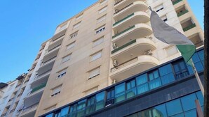 A multi-story building with a modern architectural design, featuring balconies and large windows. - Bright and Cozy Apartment in a Central Location (Béjaïa)