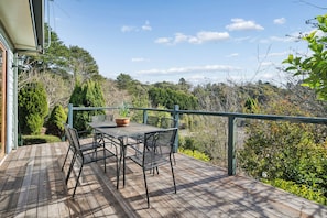 Eine Holzterrasse mit Tisch und Stühlen mit Blick auf ein bewaldetes Gebiet.