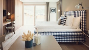 Een slaapkamer met een bed, bureau, stoel, lamp en uitzicht.