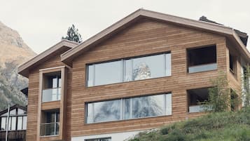 A modern wooden house with large windows and a stone base.