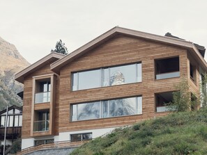 A modern wooden house with large windows and a stone base. - OVERLOOK Lodge by CERVO Zermatt, (Zermatt), by Interhome (Zermatt)