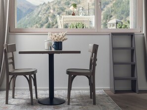 A room with a table and two chairs, a window with a view of a mountainous landscape, and a ladder against the wall. - OVERLOOK Lodge by CERVO Zermatt, (Zermatt), by Interhome (Zermatt)