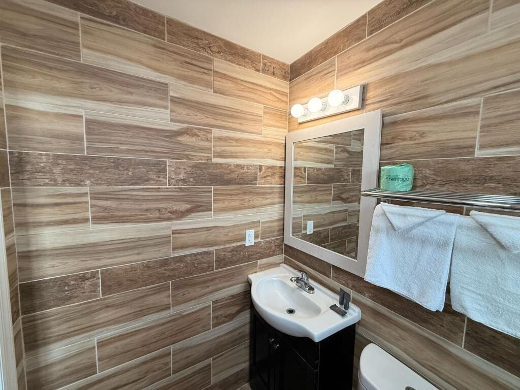 Um banheiro com design de parede de madeira, uma pia, um espelho e um porta-toalhas.