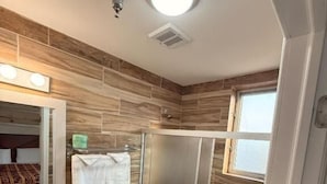 A bathroom with a shower, toilet, sink, and a mirror.