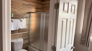 A bathroom with a shower, toilet, and towel rack.