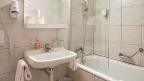 Un baño con lavamanos, espejo, toallero, inodoro y zona de ducha.
