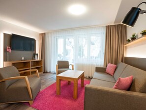 Uma sala de estar moderna com um sofá, poltronas, uma mesa de centro e uma televisão.