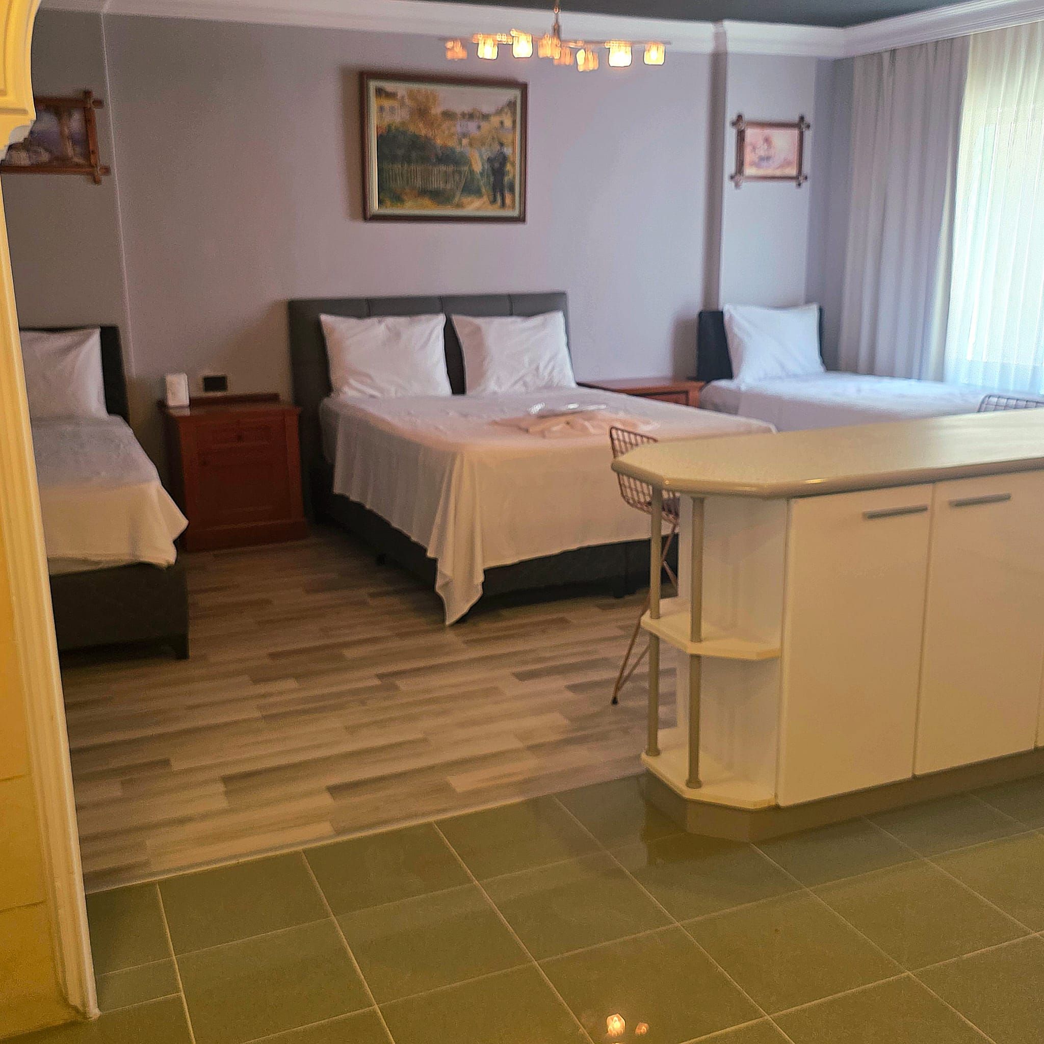 A hotel room with two beds, a small desk, a chair, and a painting on the wall.