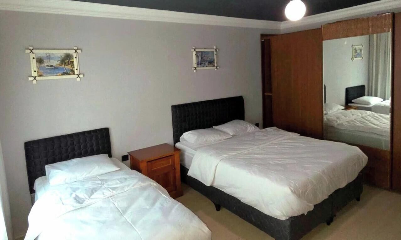 Una habitación de hotel con dos camas, una mesita de noche de madera y un espejo grande.