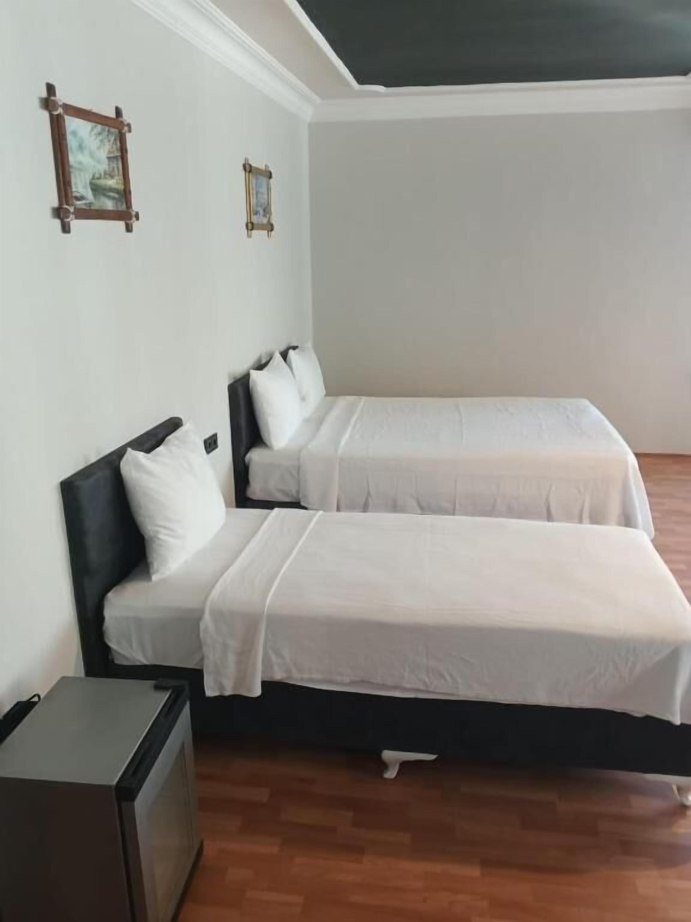 Een kamer met twee bedden, een kleine tafel en een tv aan de muur.