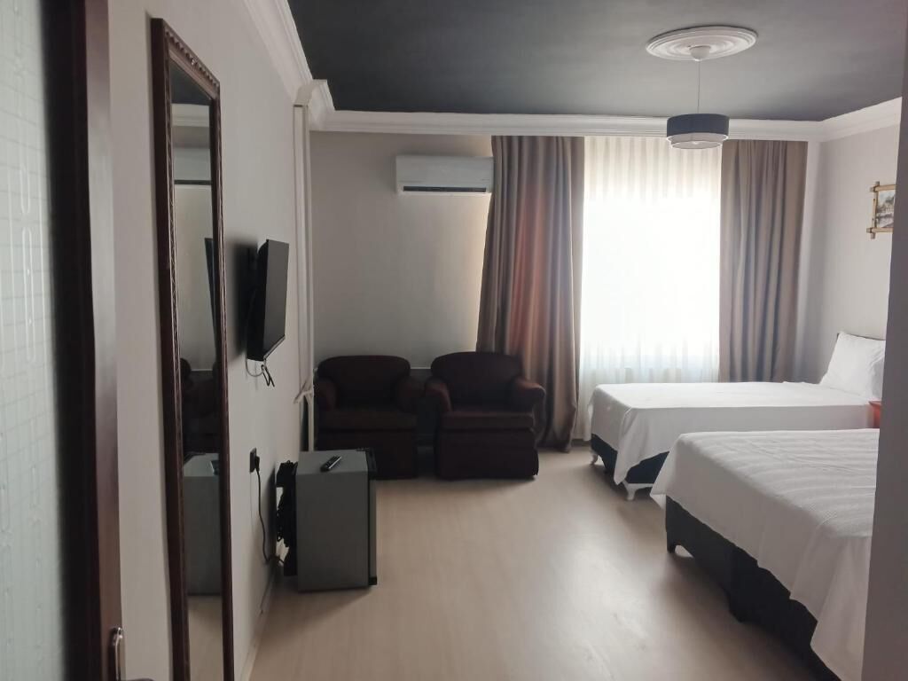 Une chambre d’hôtel équipée d’un lit, d’un bureau, d’une chaise, d’un climatiseur et d’un téléviseur.