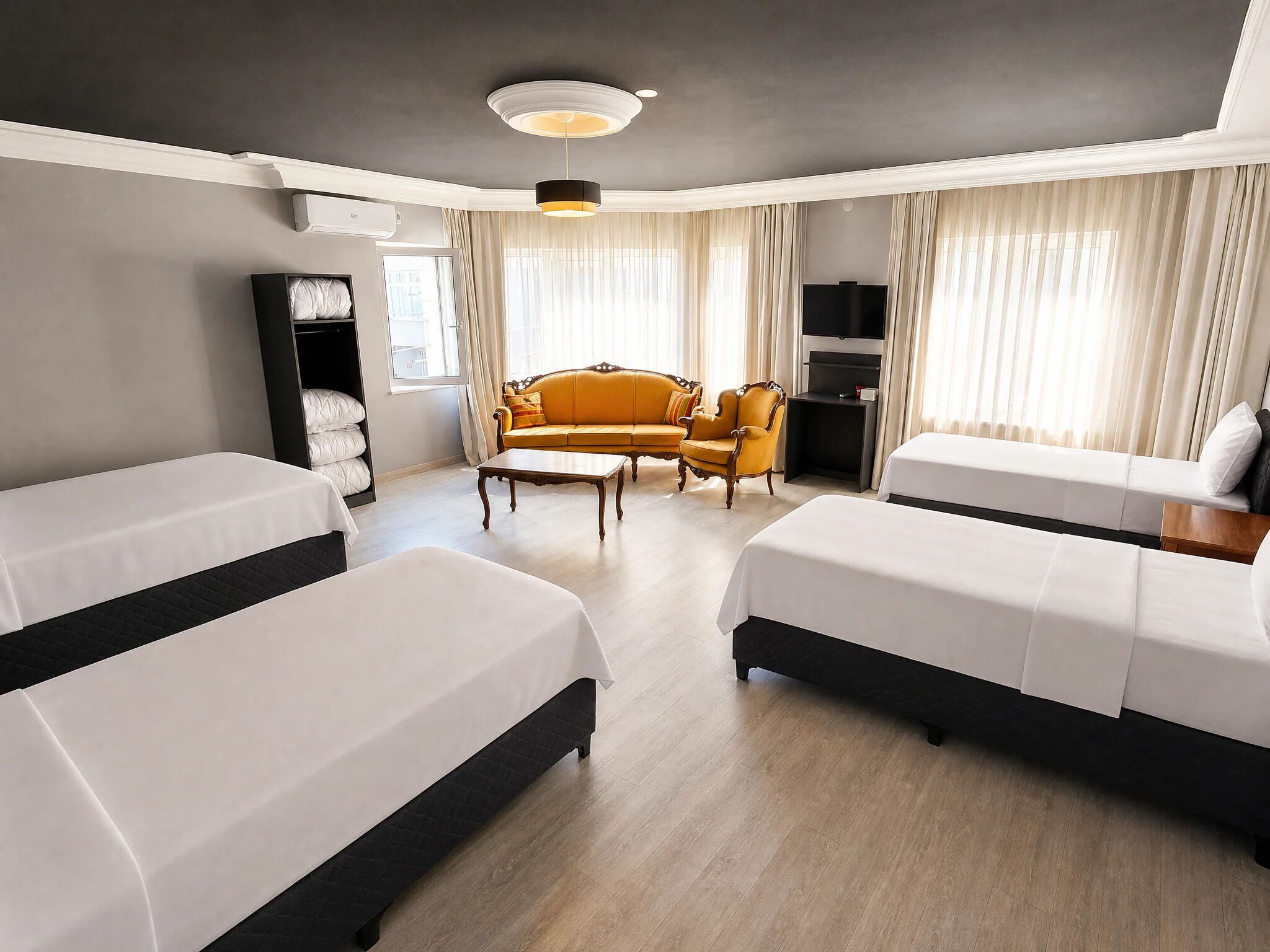 Habitación de hotel con dos camas, un sofá, una silla, un televisor y un armario.