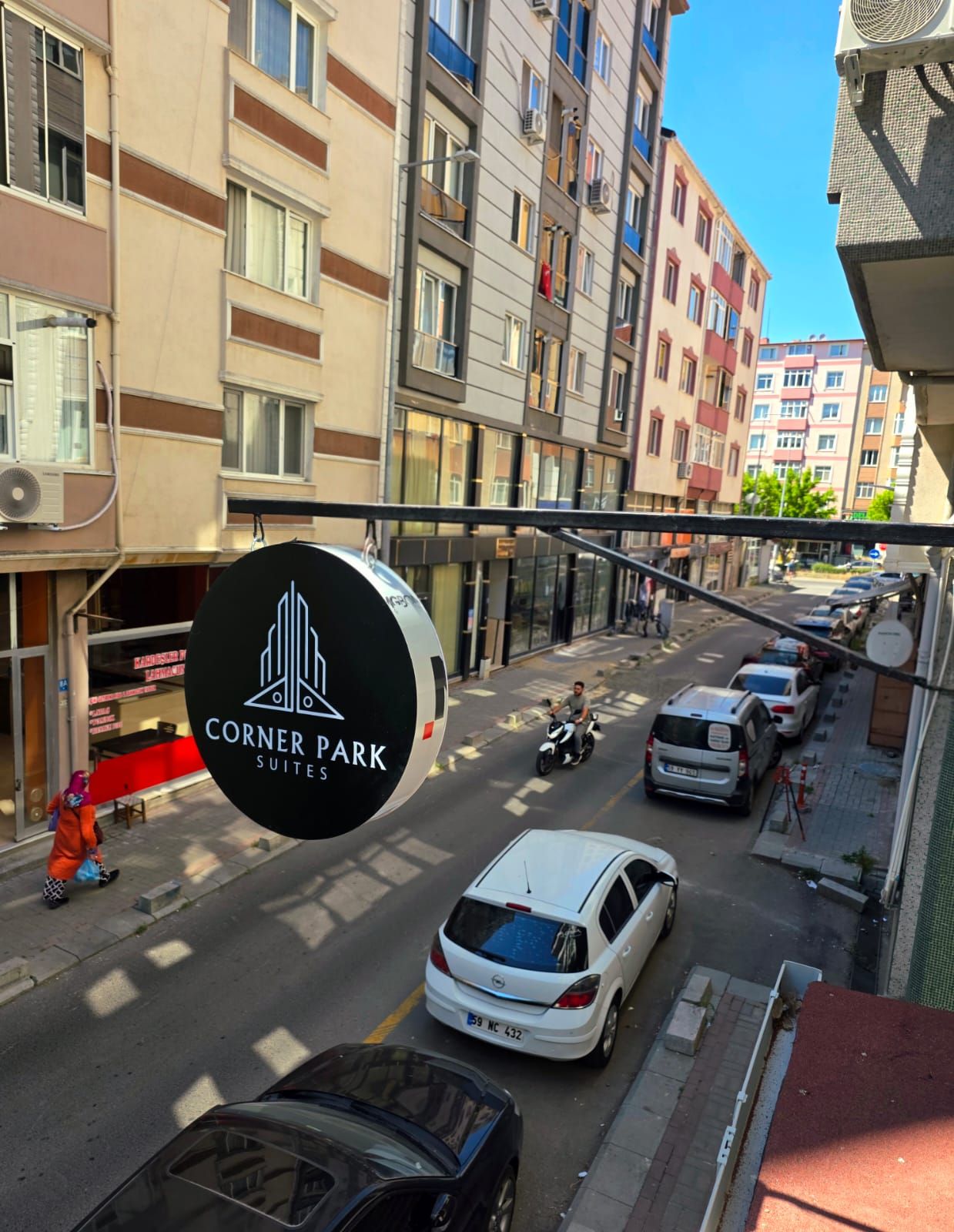 Kadunäkymä, jossa näkyy kyltti, jossa lukee ”Corner Park Suites”, mikä viittaa hotelliin tai muuhun majoituspaikkaan.