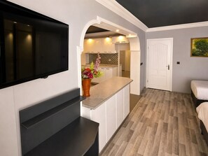 Una cocina moderna con televisión integrada, un arreglo floral y piso de madera.