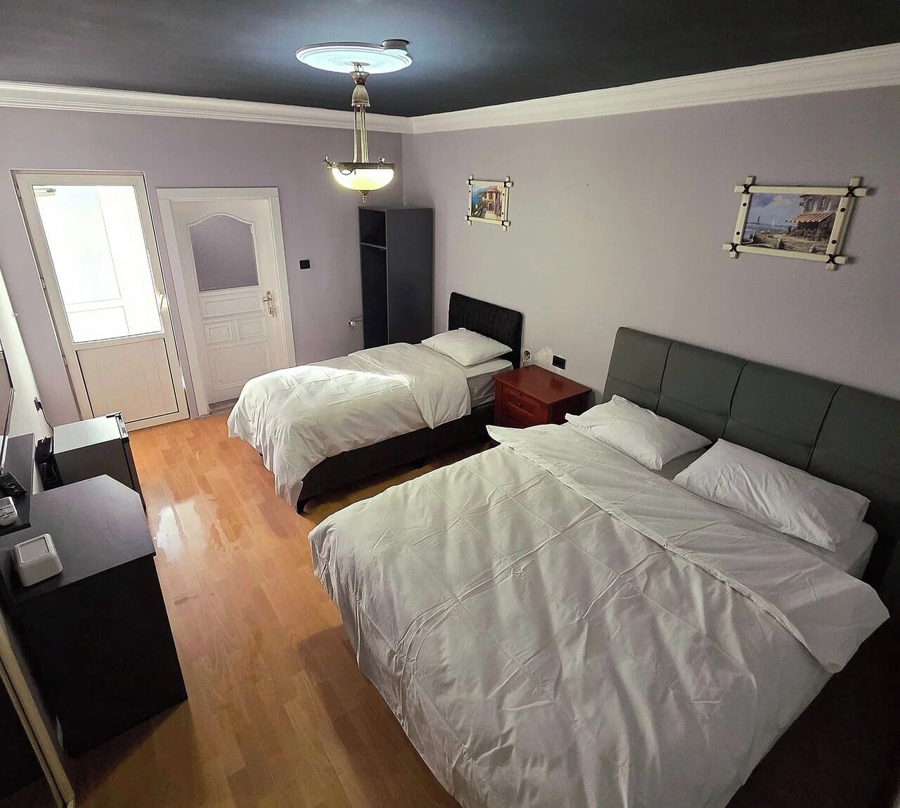 A room with two beds, a desk, a wardrobe, and a ceiling fan.