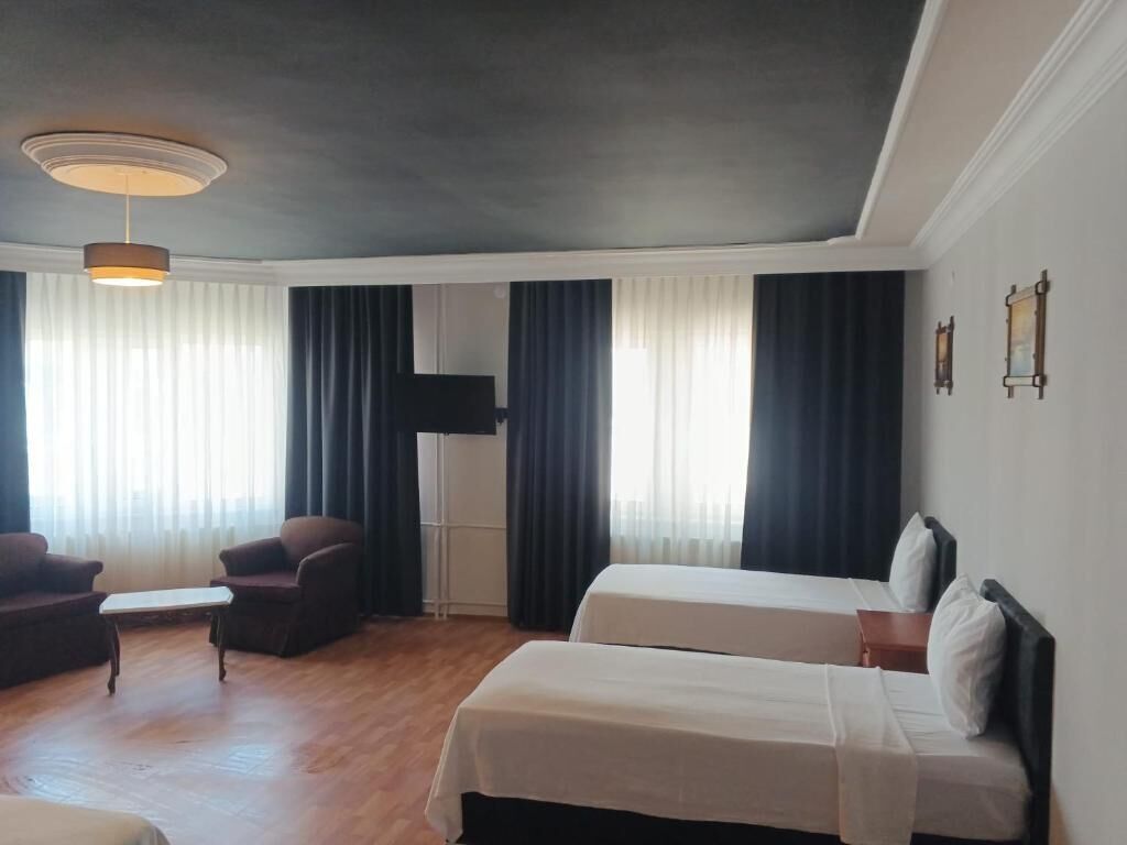 Una habitación de hotel con dos camas, un sofá, una mesita y una lámpara en el techo.