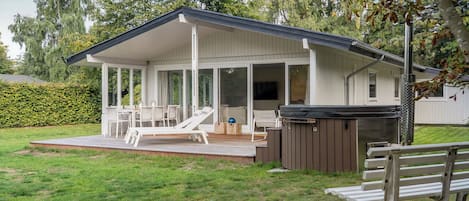 A covered outdoor area with a pool table, lounge chairs, and a hot tub.