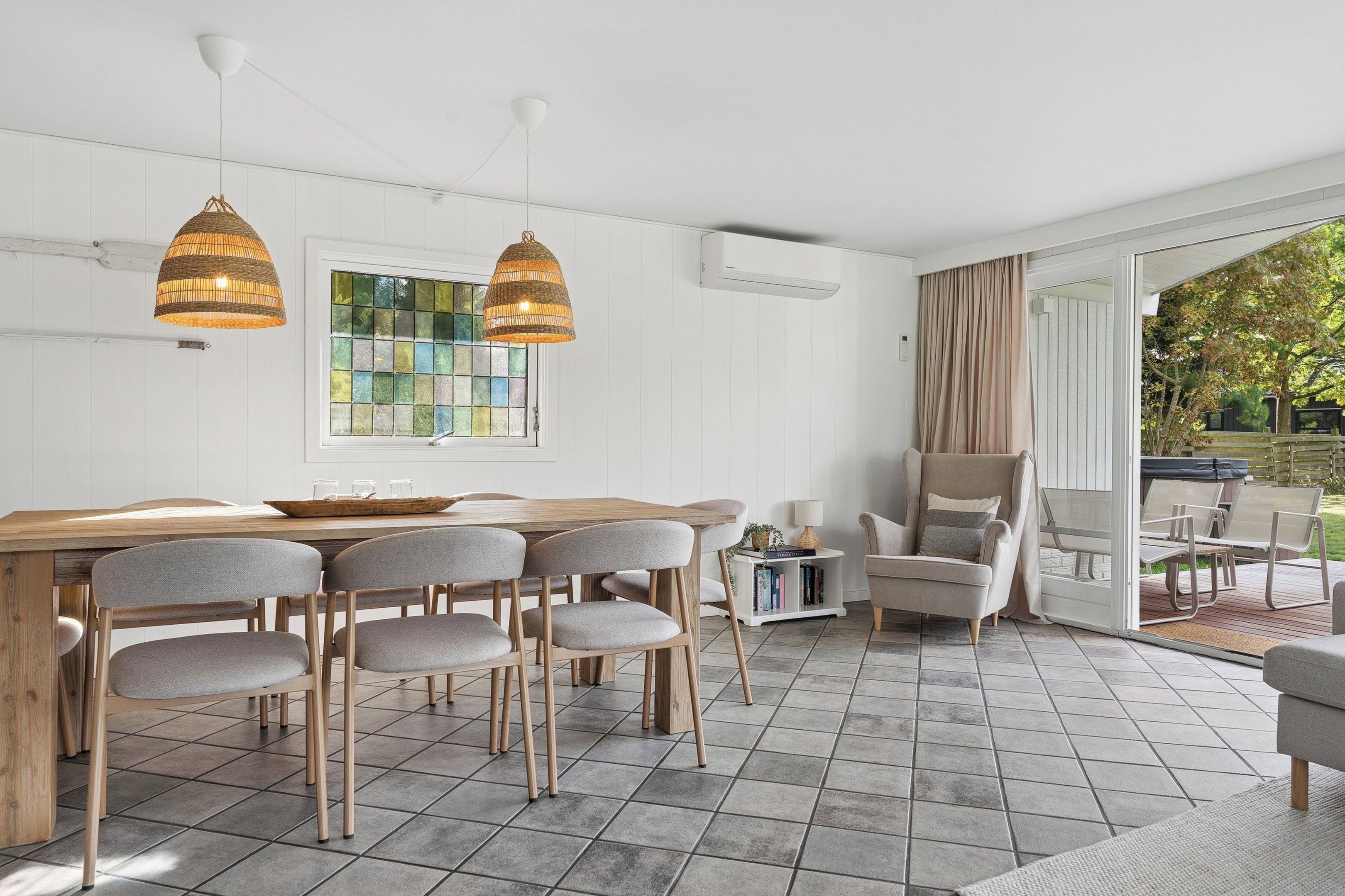Een eethoek met een houten tafel, grijs gestoffeerde stoelen en twee hanglampen.