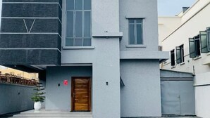 A modern two-story building with a flat roof, large windows, and a wooden door. - Defivez hotel  (Lekki)