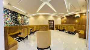 A hotel lobby with a central seating area, a large abstract mural, and a wooden panel wall. - Defivez hotel  (Lekki)