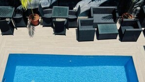 A swimming pool with the text 'FIVE ZONES' and outdoor wicker furniture. - Defivez hotel  (Lekki)