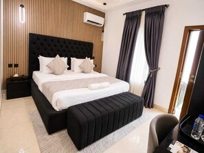 Habitación de hotel moderna con una cama grande, una mesita de noche, un pequeño escritorio y una silla.