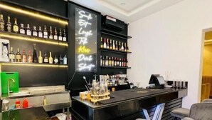 A bar area with a black counter, bar stools, and shelves of liquor bottles. - Defivez hotel  (Lekki)