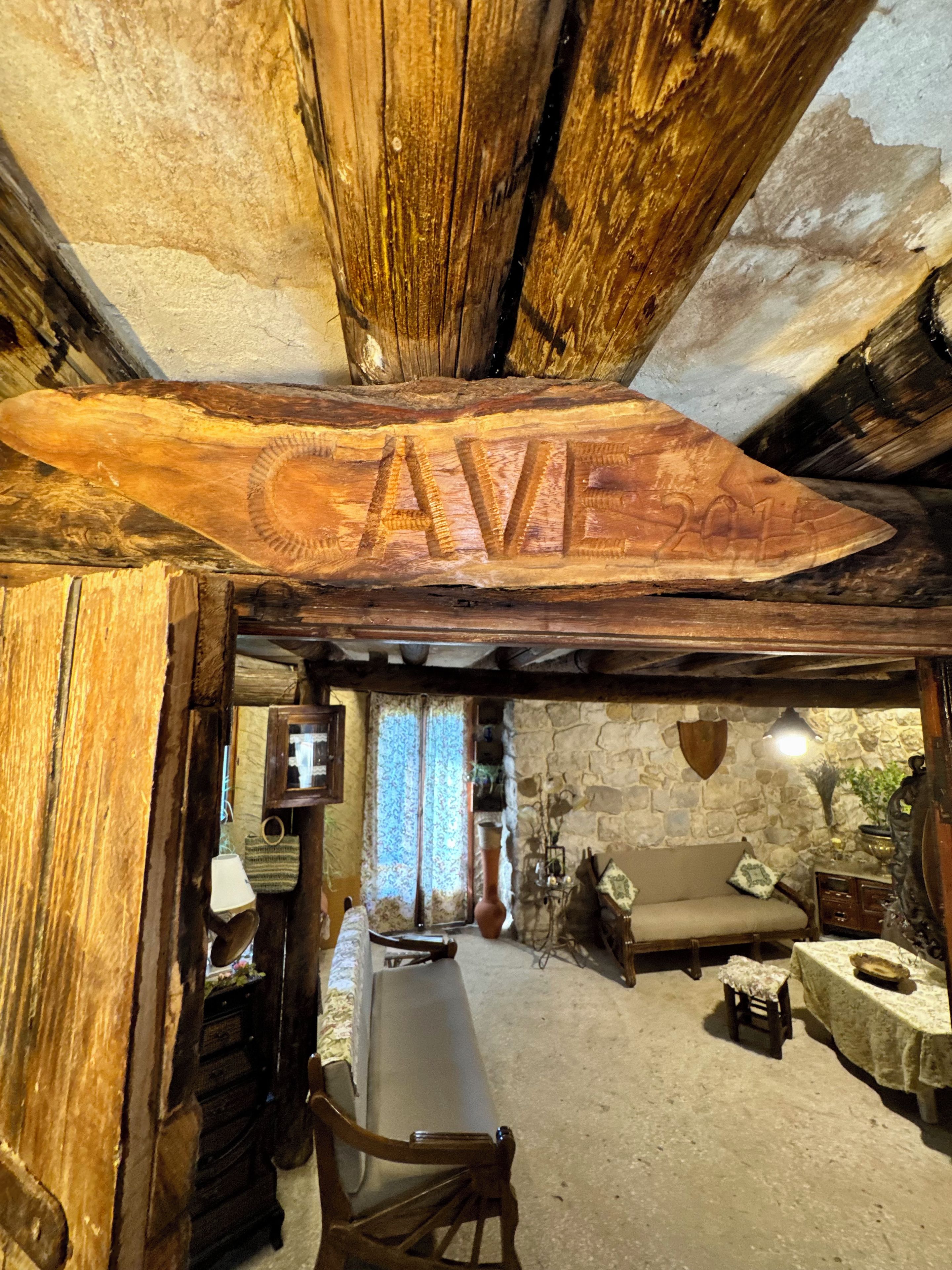 A rustic interior with exposed wooden beams, a stone wall, a sofa, and a table.