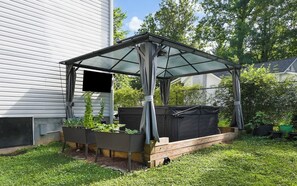 A covered garden area with raised beds, a wooden deck, and a house in the background. - Mountain View Retreat with Hot Tub,Pet-Friendly,Near Asheville & Biltmore (Arden)